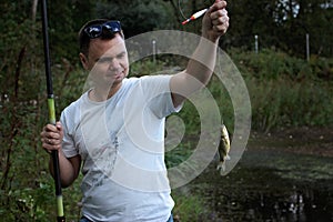 Adult man catching a fish on the lake