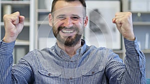 Adult man celebrating success gesture in office