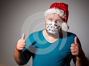 Adult man in Christmas decorated mask, Gesturing Thumbs Up. celebrate xmas holidays at home because coronavirus.