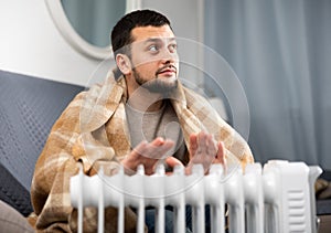 Adult man with cup near heater in home closeup