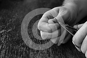 An adult man is cutting his hand nails with manicure scissors