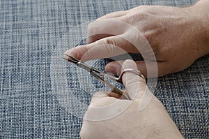 Adult man is cutting his own hand nails with manicure scissors