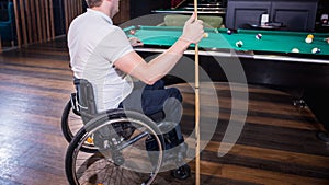 Adult man with disability in a wheelchair play billiards in the club