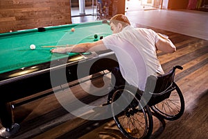 Adult man with disability in a wheelchair play billiards in the club