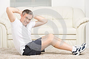 Adult man doing sit ups on floor.