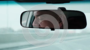 Adult man driving car. Cinematic shot of car driver face in rearview mirror.