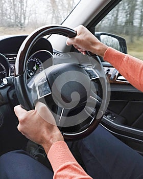 Adult man driving a car, close up on hands holding a steering wheel. Driving examination, exam, driving license