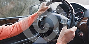 Adult man driving a car, close up on hands holding a steering wheel. Driving examination, exam, driving license