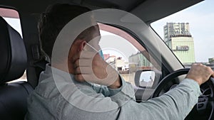 Adult man driving car wearing protective face mask during the coronavirus epidemic.