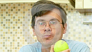 Adult man eating a green apple with pleasure.