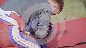 An adult man folds his parachute