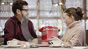 Adult man gives a box of flowers to his happy wife and she kisses him