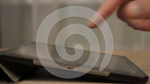 Adult man hand activating a tablet computer the touchscreen with a finger while surfing the internet or inputting data