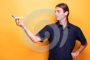 Adult man loking at his toy airplane in his right hand