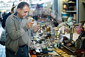 Adult man is looking antiquariat at the market of old things.