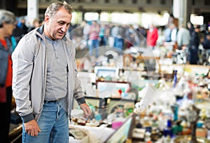 Adult man is looking antiquariat at the market of old things.