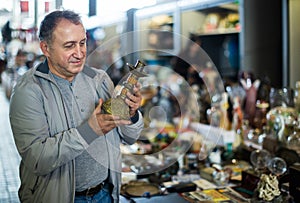 Adult man is looking antiquariat at the market of old things.