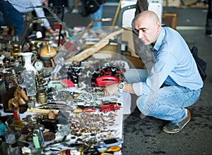 Adult man is looking antiquariat at the market of old things.