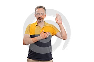 Adult man making honest oath gesture touching heart showing palm