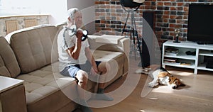 adult man and mature senior working his body with dumbbell - one man happy training indoors sitted on the sofa