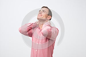 Adult man in pink shirt having neck pain because of osteochondrosis, hernia or spasm