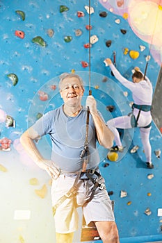 Adult man posing with safety rope on climbing wall