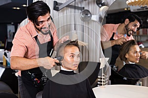 Adult man professional shaving woman`s hair