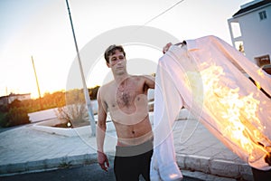 Adult man pyromaniac burning his shirt on the street
