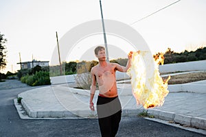 Adult man pyromaniac burning his shirt on the street