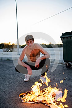 Adult man pyromaniac burning his shirt on the street