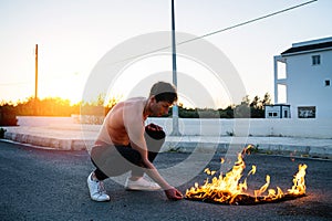 Adult man pyromaniac burning his shirt on the street