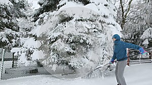 Adult man removing snow from trees in garden