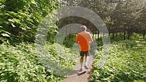 Adult man running jogging outdoors in a forest nature on a forest trail and enjoying it and looking happy