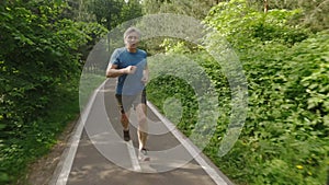 Adult man running jogging outdoors in a forest nature on a forest trail and enjoying it and looking happy