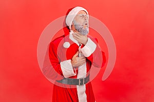 Adult man in santa claus costume touching neck, suffering from unpleasant sore throat pain, tonsillitis, thyroid, inflammation