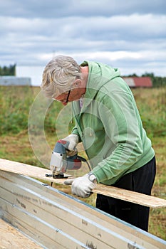 An adult man sawing boards electric jigsaw for building a house