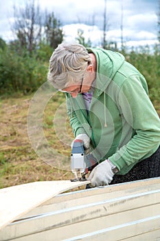 An adult man sawing boards electric jigsaw for building a house