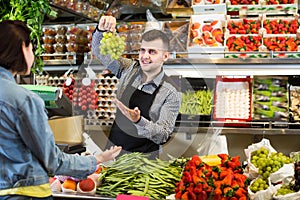 Adult man seller helping customer to buy fruit