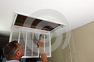 Adult Man Shining Flashlight Into HVAC Intake Vent in a Home Entry