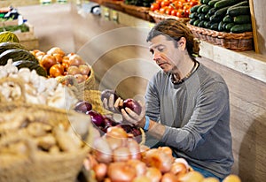 Adult man shopper chooses onions in shop