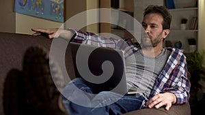 Adult man sitting on sofa with computer on lap thinking, future plans, choice