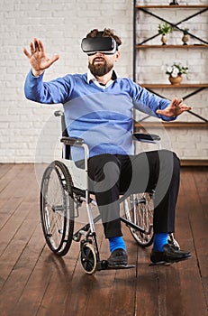 Adult man sitting in a wheelchair and using a VR headset