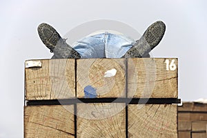 Adult man sleeping on a stack of wood