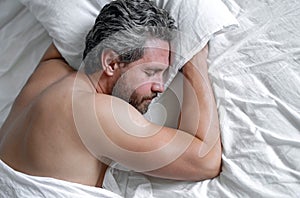 Adult man sleeps in white bed. Handsome shirtless man sleeping in bed at bedroom. Hispanic mature man sleeping at home