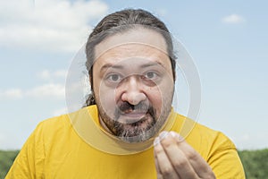 An adult man with a small beard demonstrates his severe irritation with a gesture