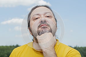 An adult man with a small beard demonstrates his severe irritation with a gesture