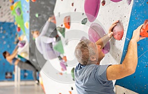 Adult man practicing rock climbing on climbing wall