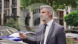 Adult man standing outdoors and giving a business card for lady. Slow motion