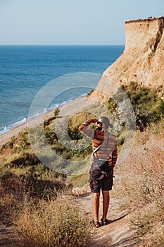 Adult man in sweater walking outdoors the rocky coast near sea
