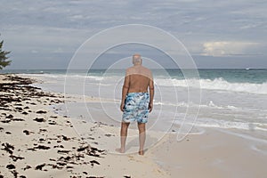 Adult Man in Swim Trunks Looking at the Caribbean Sea